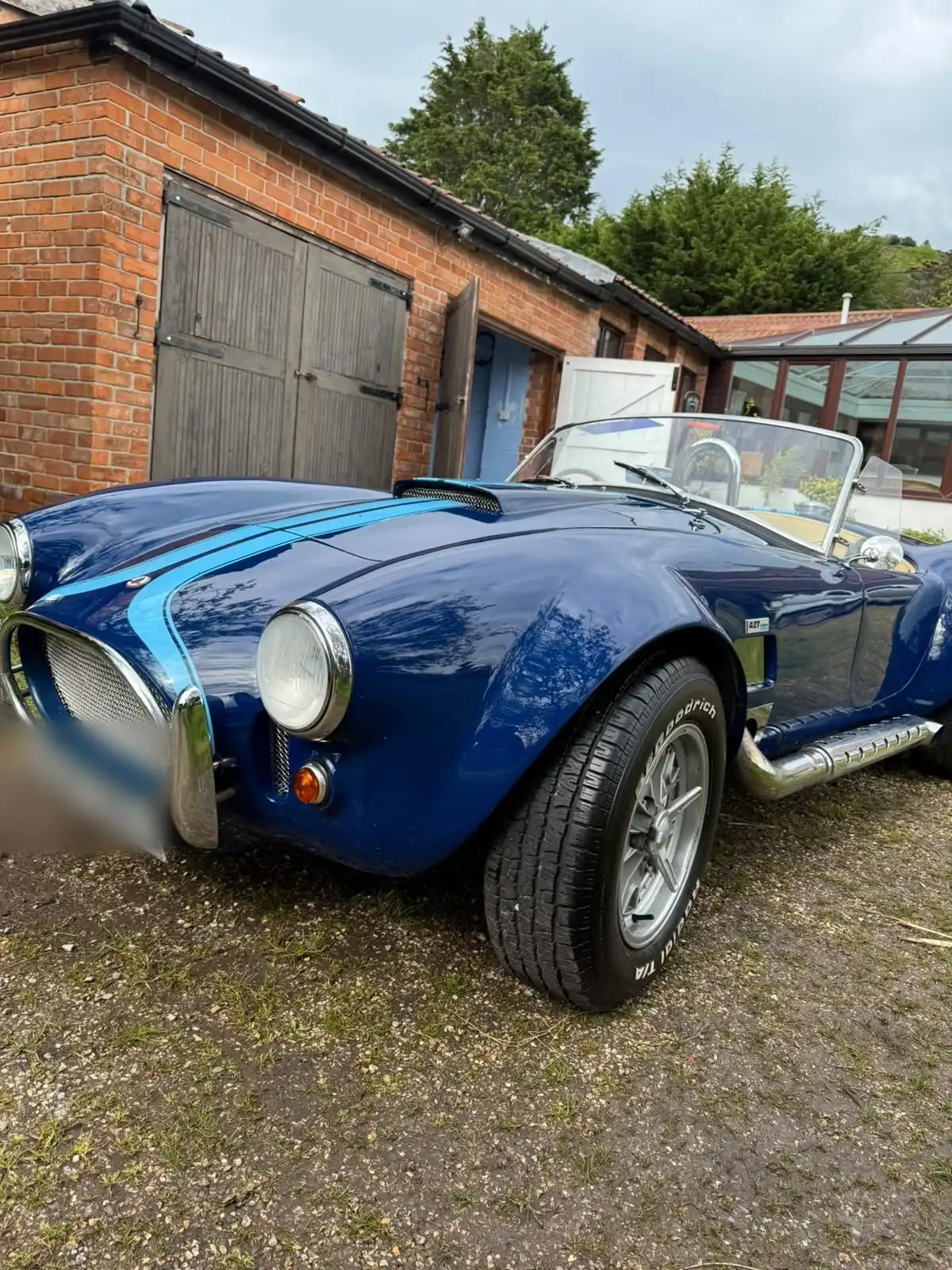 Blue AC Cobra replica with white stripes, front quarter view, an example of a classic car