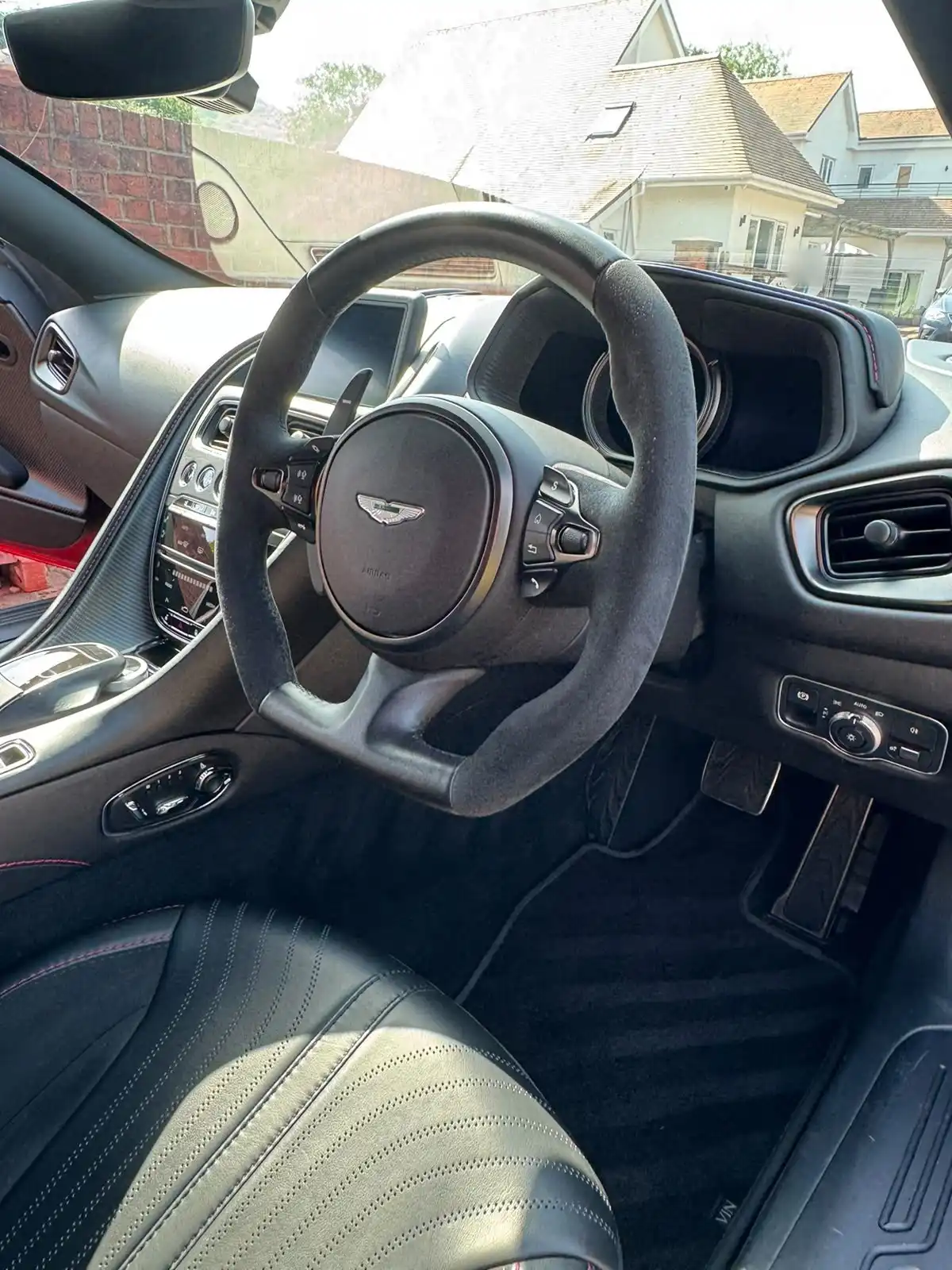 Aston Martin DB11 cabin with the steering wheel, dashboard and perforated leather seat, an example of interior work
