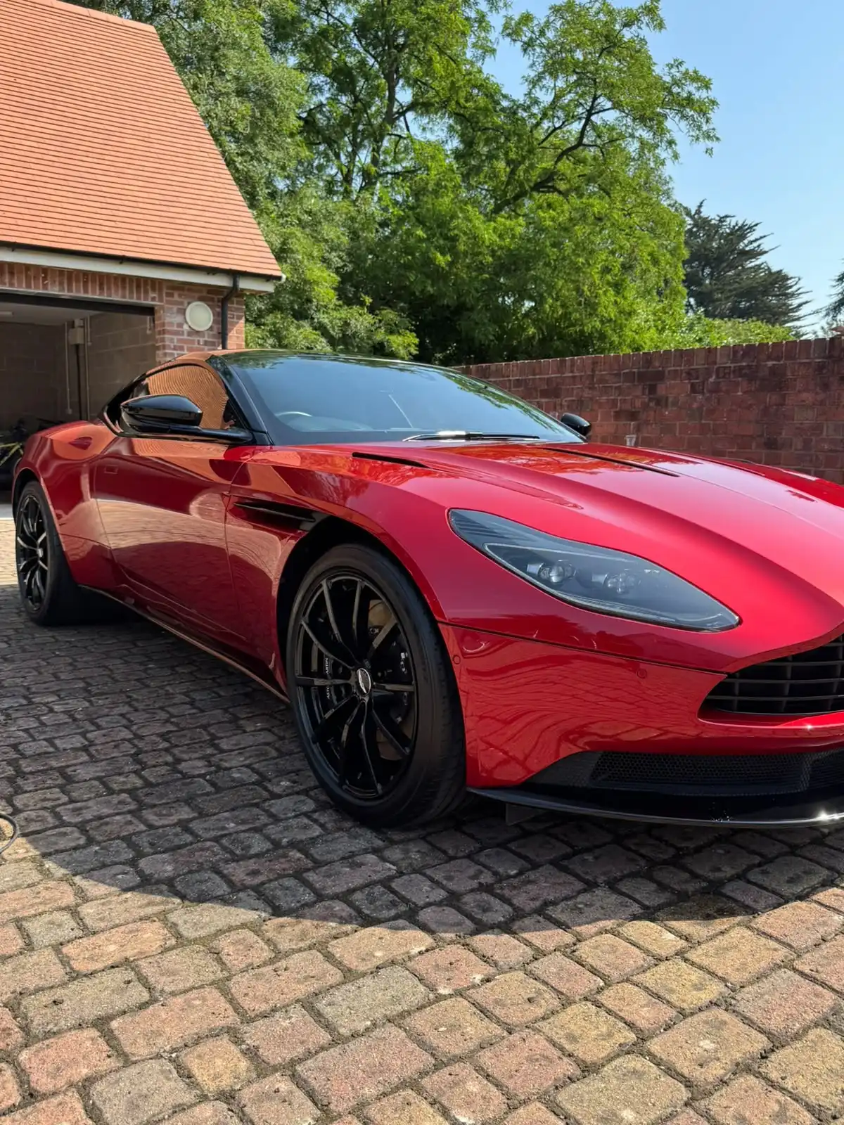 Red Aston Martin DB11 from the front three quarter, showing the depth of gloss on its paintwork
