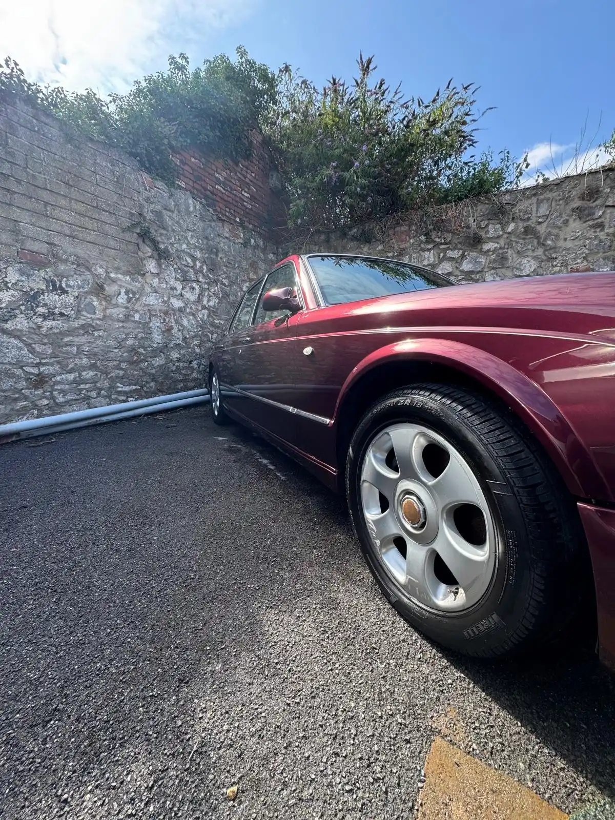 Front wing and wheel of a burgundy Bentley Arnage, showing the reflections in the paint and the clean alloy