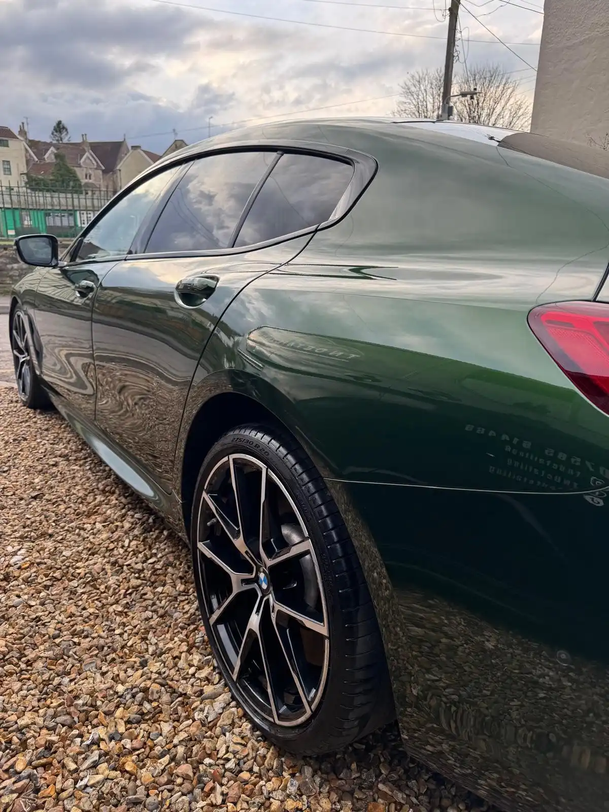 Green BMW 8 Series Gran Coupe from the rear quarter, showing clear reflections along the doors and rear wing