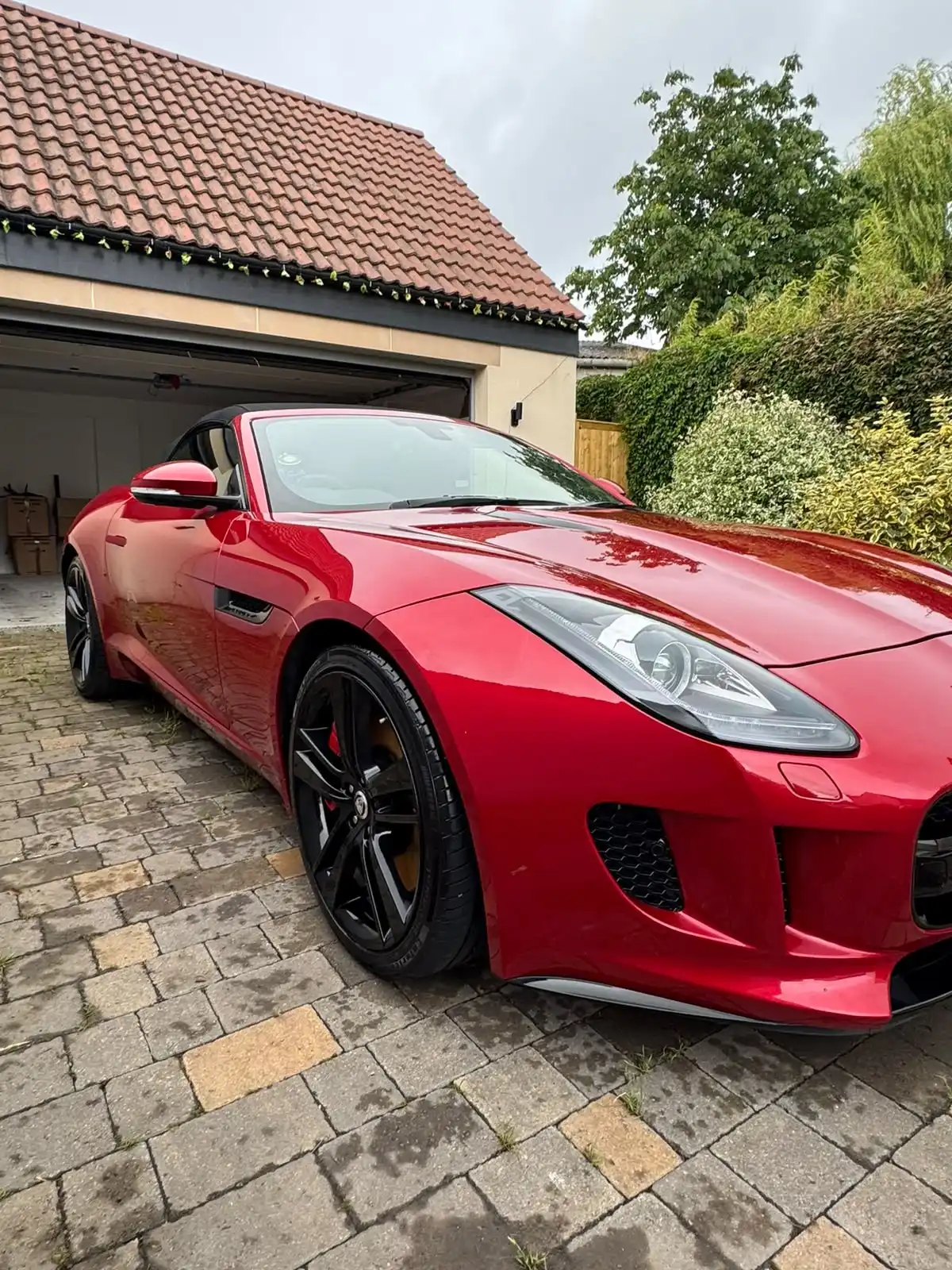 Red Jaguar F-Type convertible from the front three quarter, with strong reflections along the paintwork