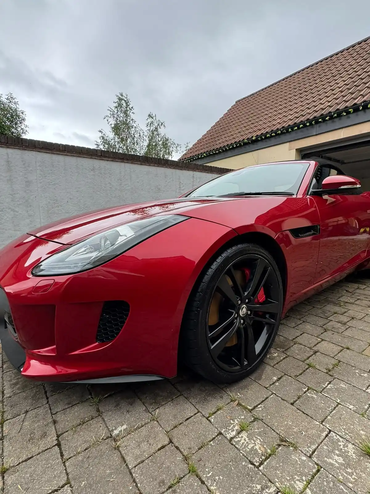Red Jaguar F-Type convertible from a low front quarter, showing the gloss on the bonnet and wing and the black alloy wheel