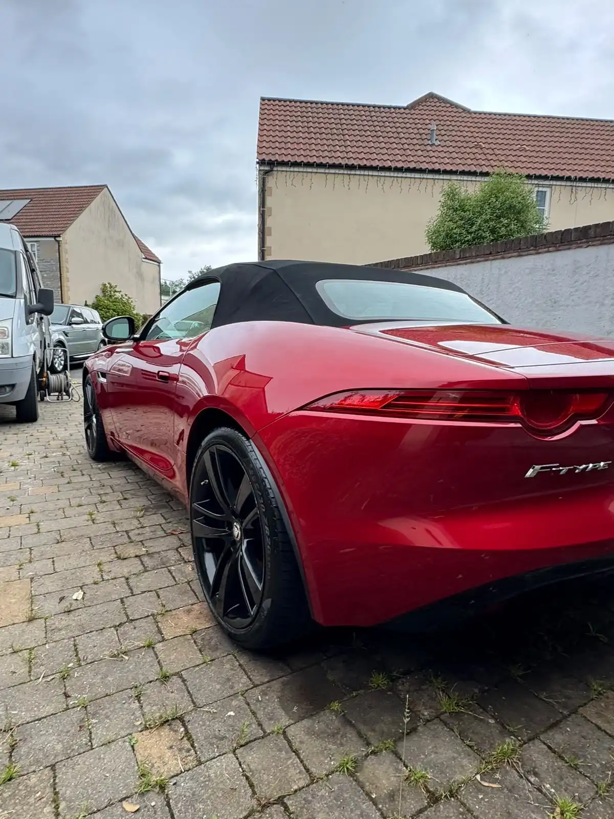 Red Jaguar F-Type convertible from the rear quarter with the roof up, showing the reflections along the rear wing