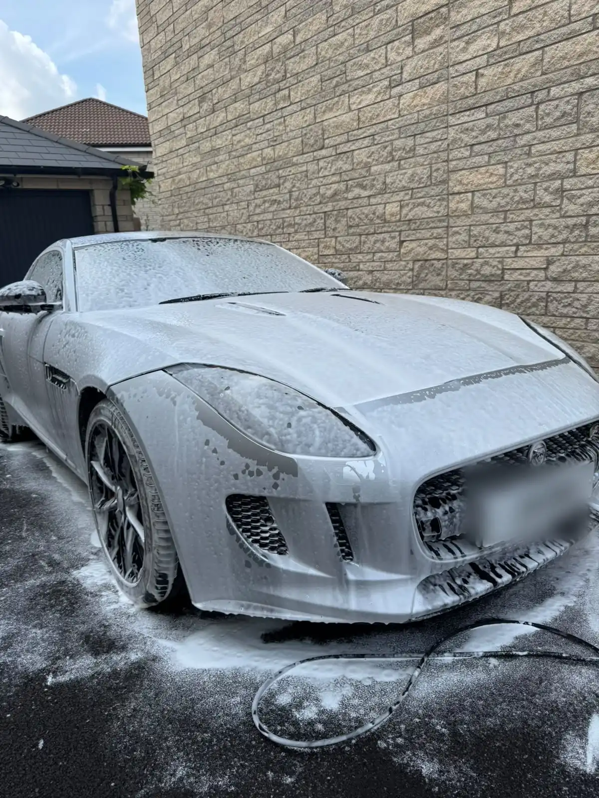 Silver Jaguar F-Type covered in snow foam, showing a stage of the wash