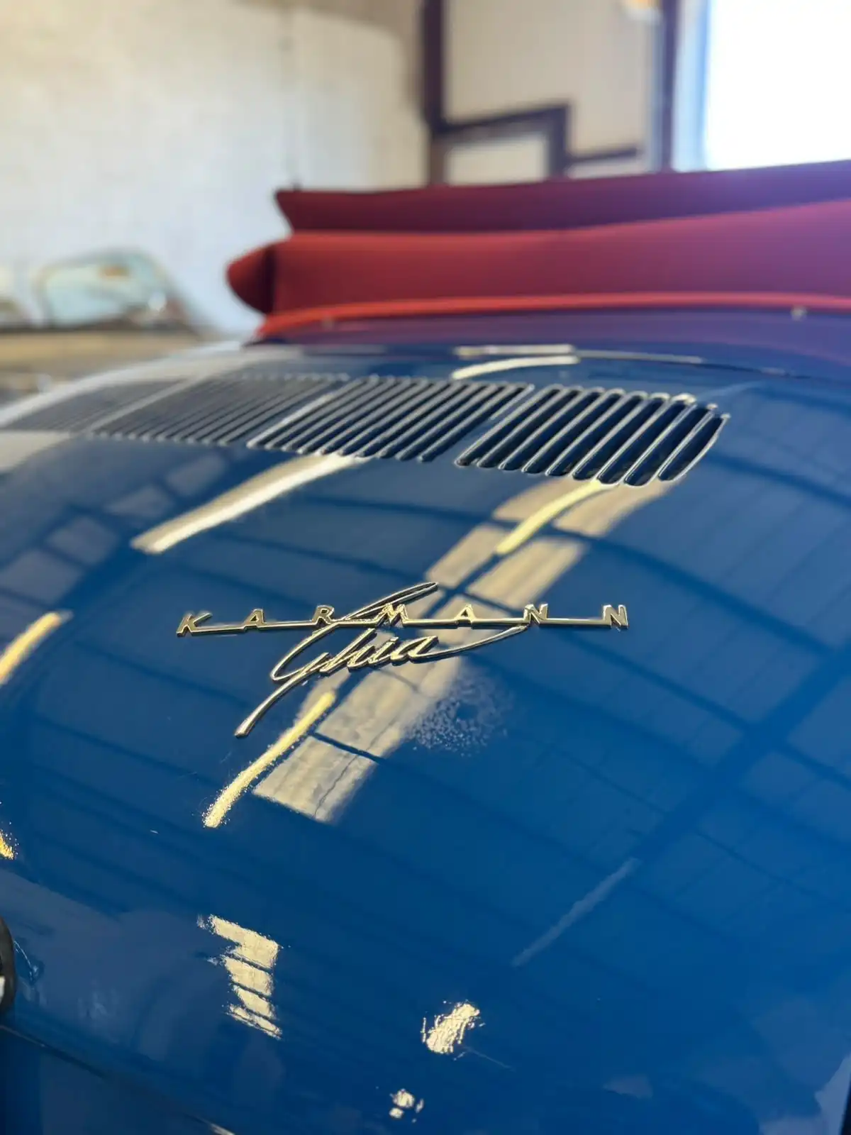 Close up of the chrome Karmann Ghia script on glossy blue paint, showing the reflections in the finish