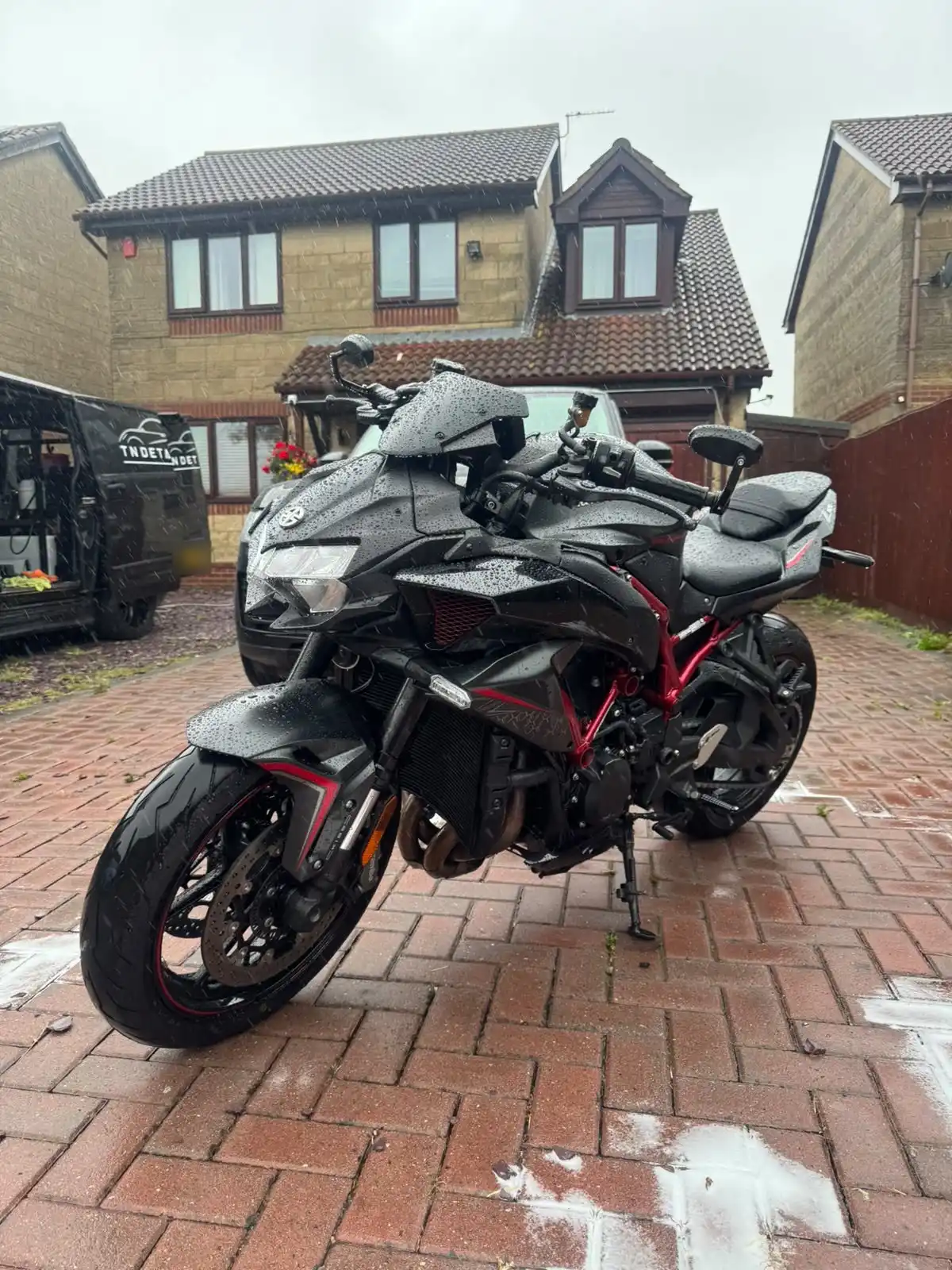 Black and red Kawasaki Z H2 from the front quarter, showing the bodywork and red frame with raindrops on the paint