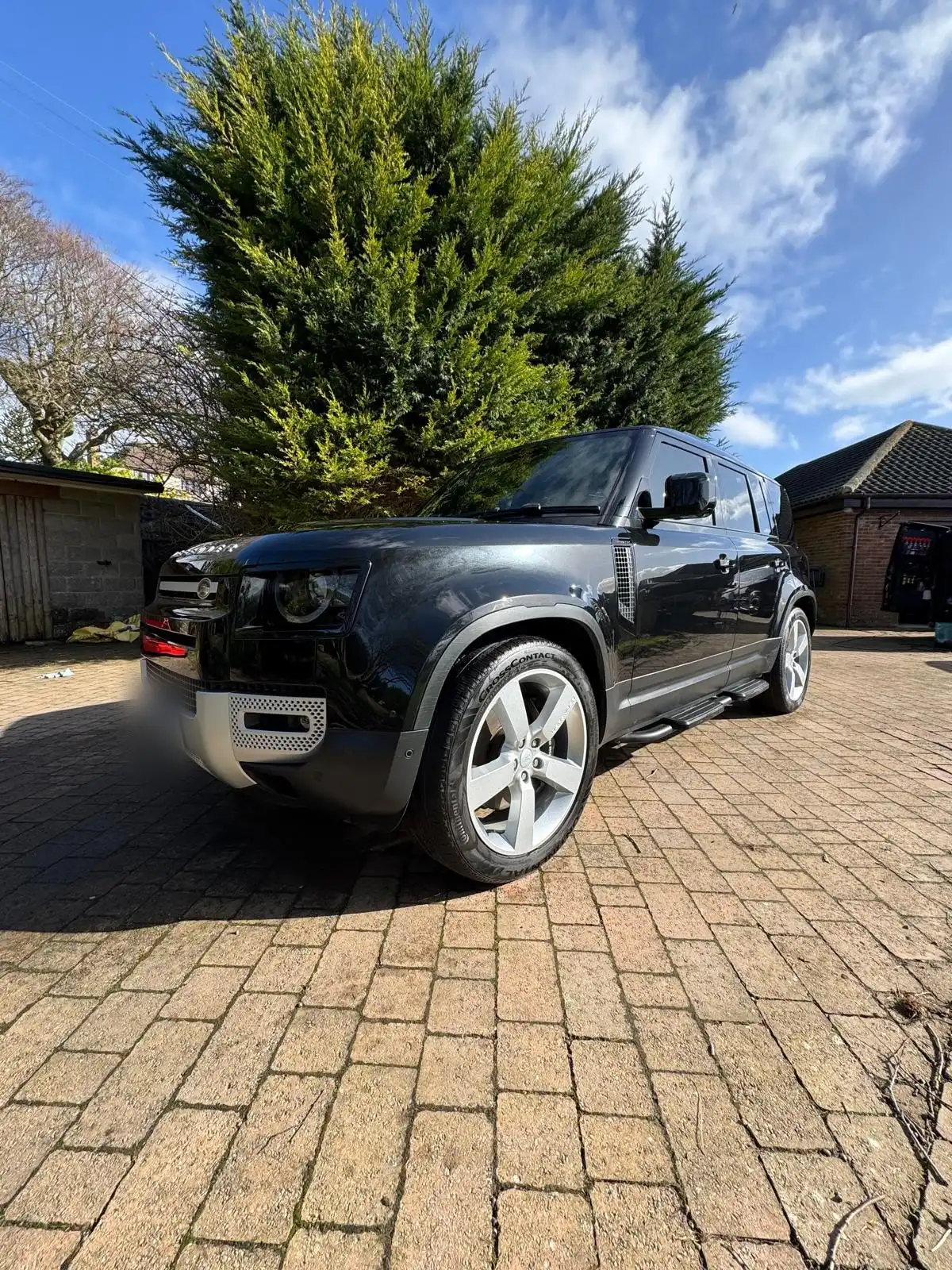 Black new shape Land Rover Defender from the front quarter, showing the black paint and the silver alloy wheel