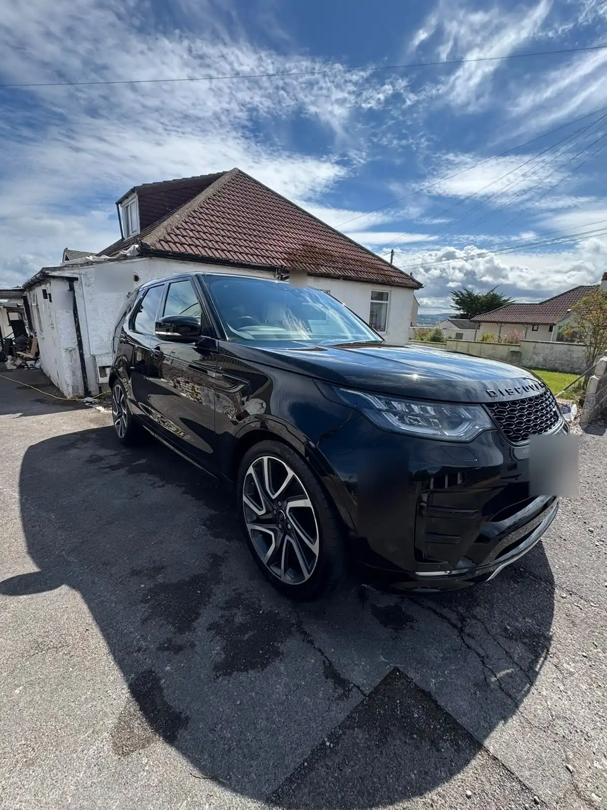 Black Land Rover Discovery from the front three quarter, showing deep gloss on the black paintwork and the two tone alloy wheels