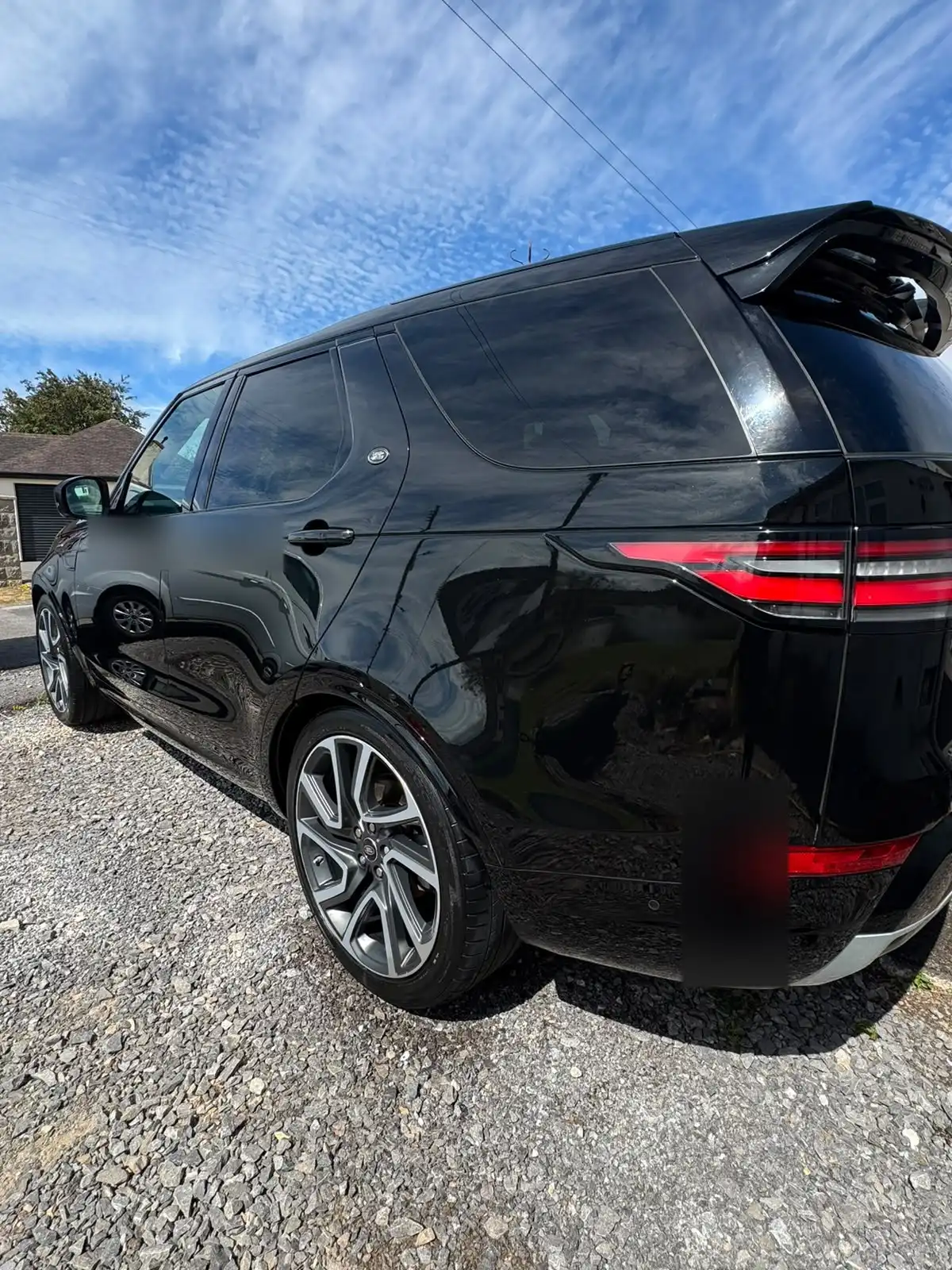 Black Land Rover Discovery from the rear quarter, showing the reflections in the gloss black doors and rear wing