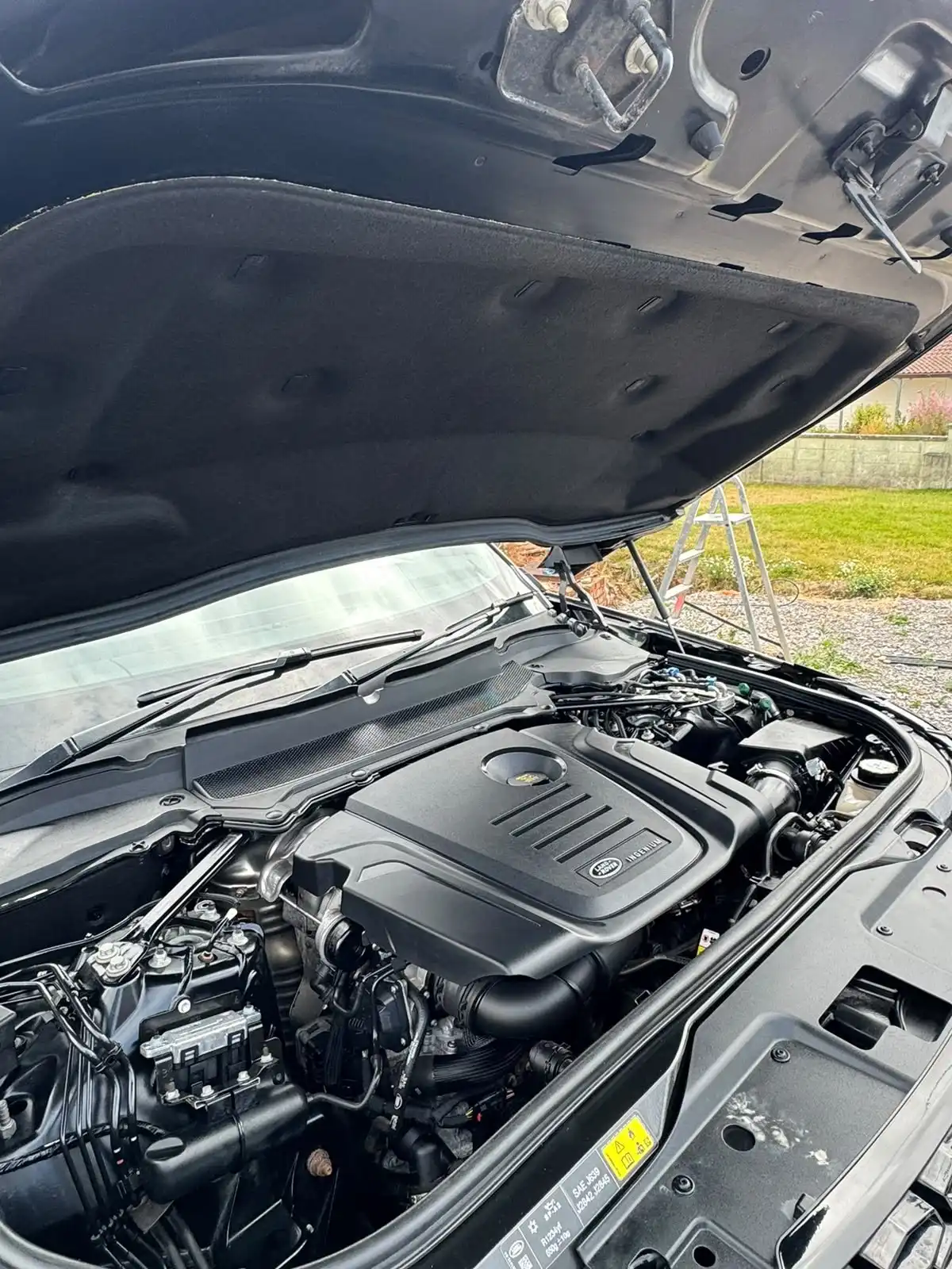 Land Rover Discovery engine bay with the bonnet open, showing the engine cover and the panels around it