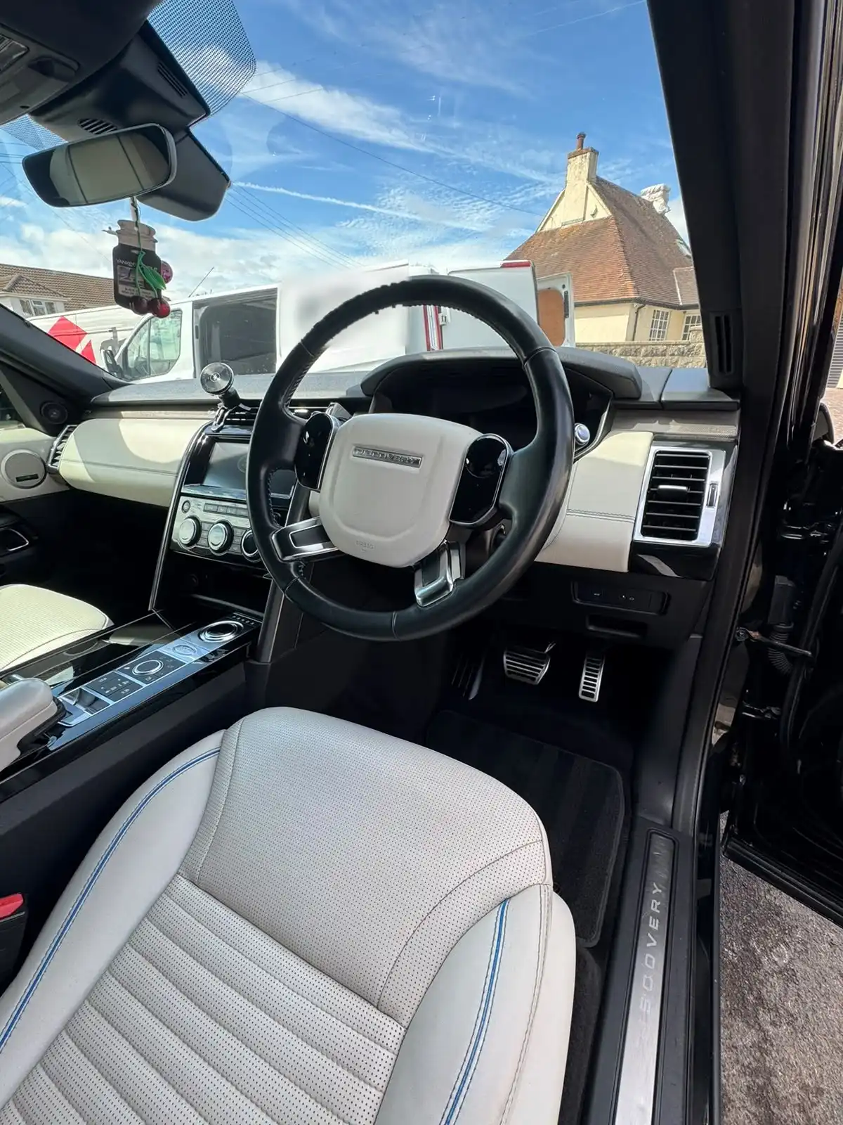 Land Rover Discovery cabin with white leather seats and blue piping, seen through the open driver door