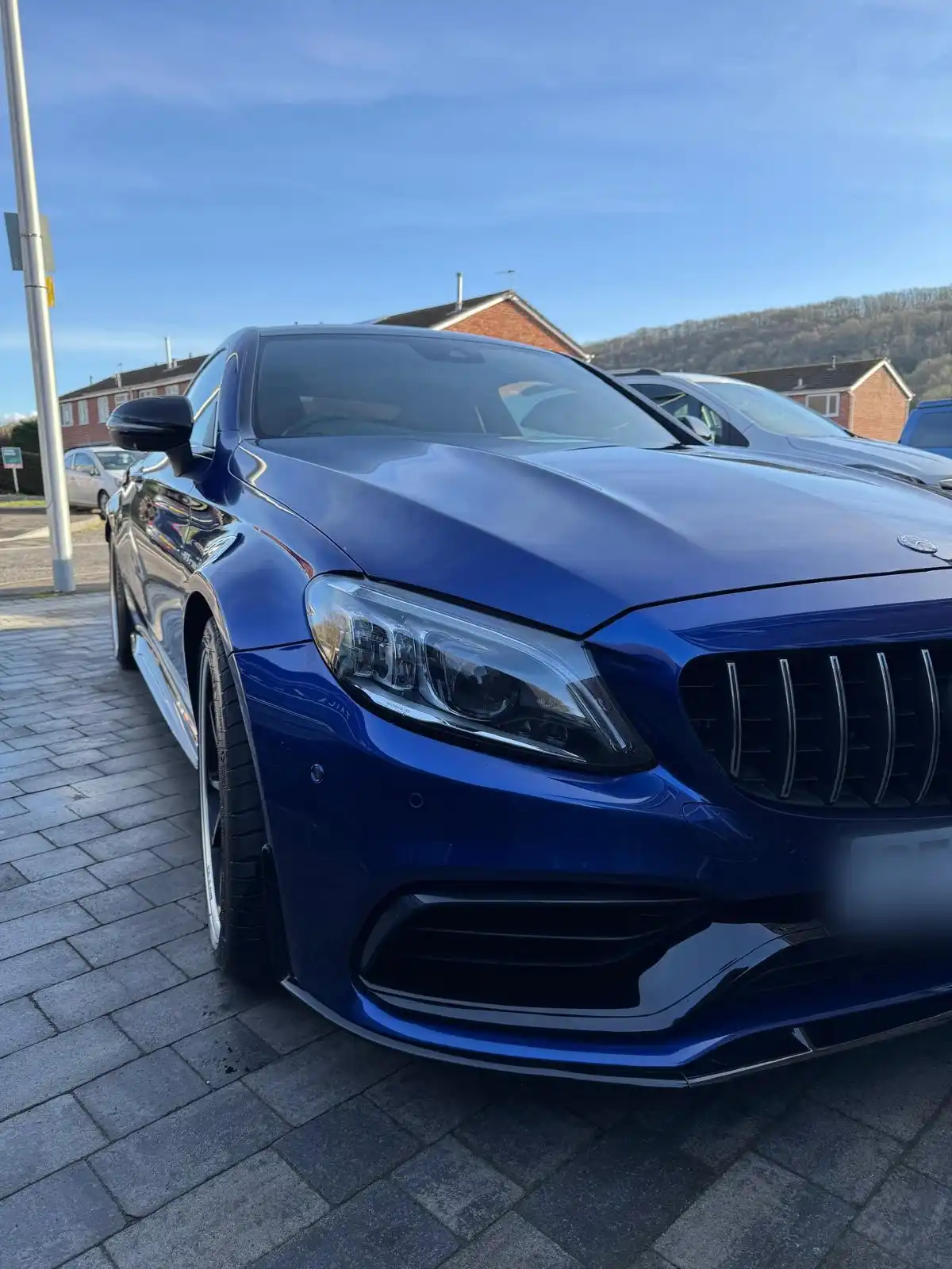 Front of a blue Mercedes-AMG C63 coupe, showing the reflections across the bonnet, grille and headlamp