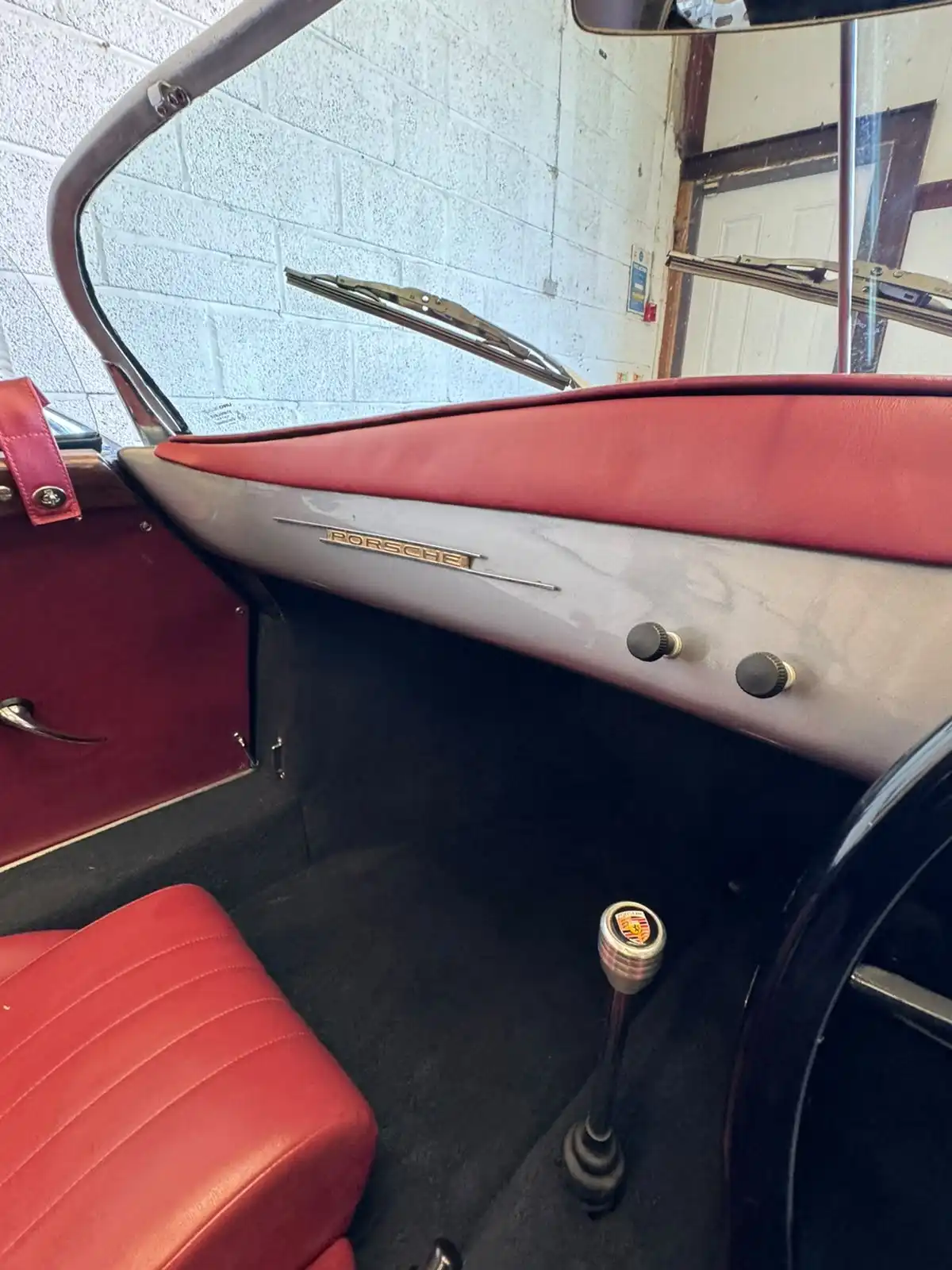 Passenger side of a Porsche 356 style speedster, showing the Porsche script on the dashboard, the red door card and the red seat