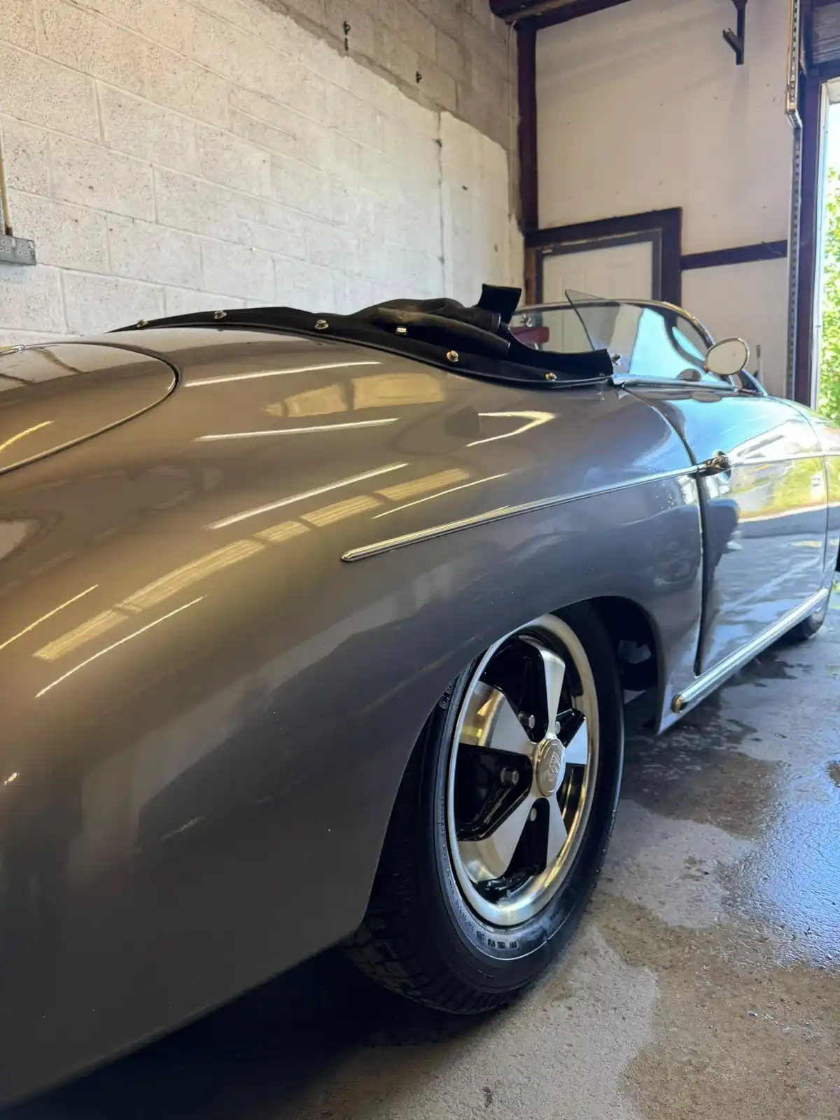 Grey Porsche 356 style speedster from the side, showing long reflections along the paintwork and the five spoke wheel