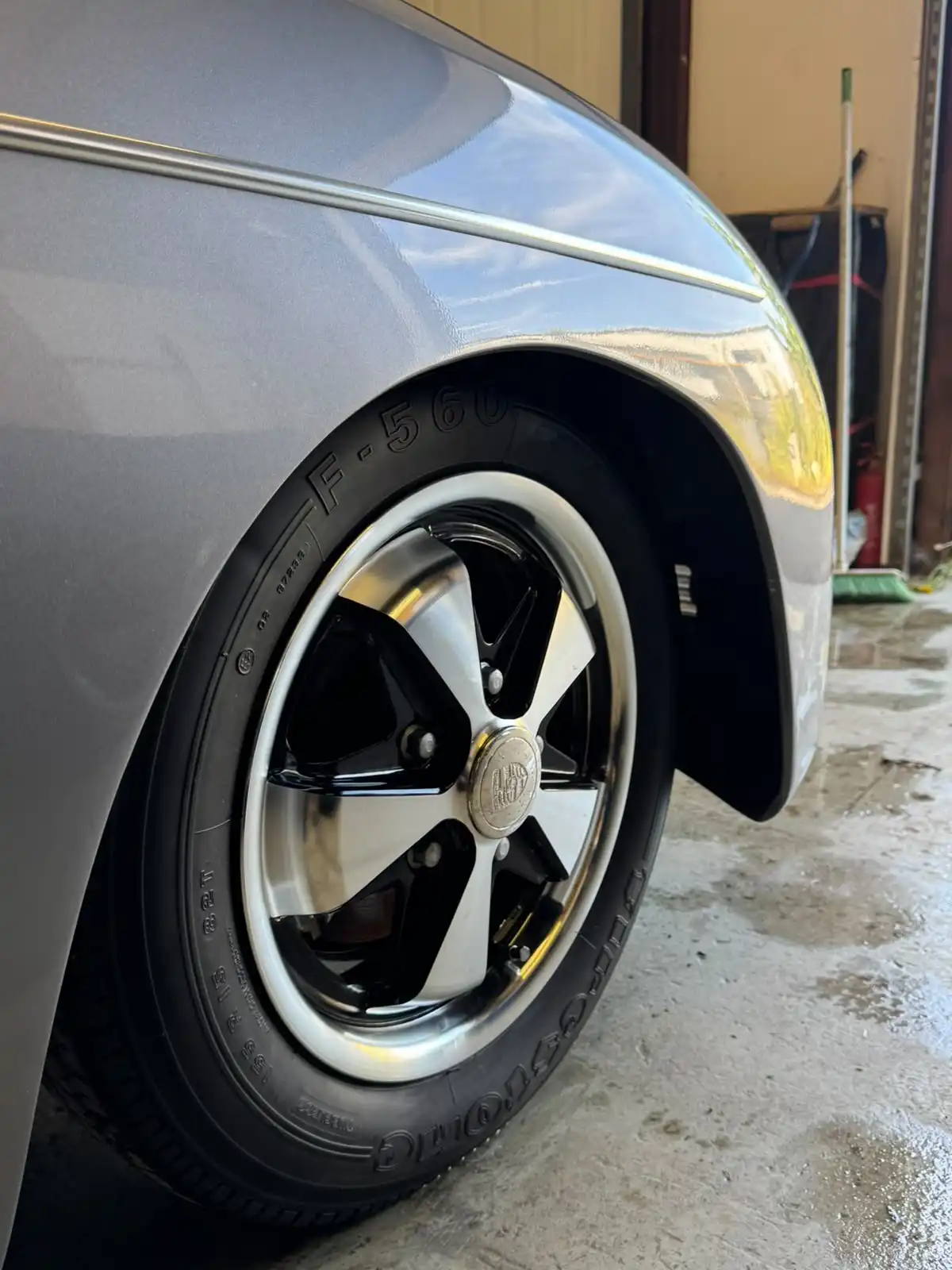 Front wheel of a grey Porsche 356 style speedster, showing the five spoke wheel and the gloss on the wing above it
