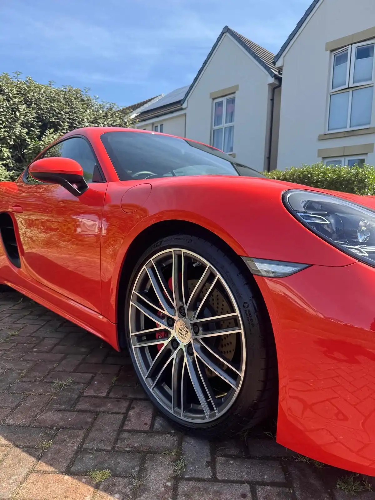 Red Porsche Cayman S from a low front quarter, showing the gloss on the wing and the multi spoke alloy wheel