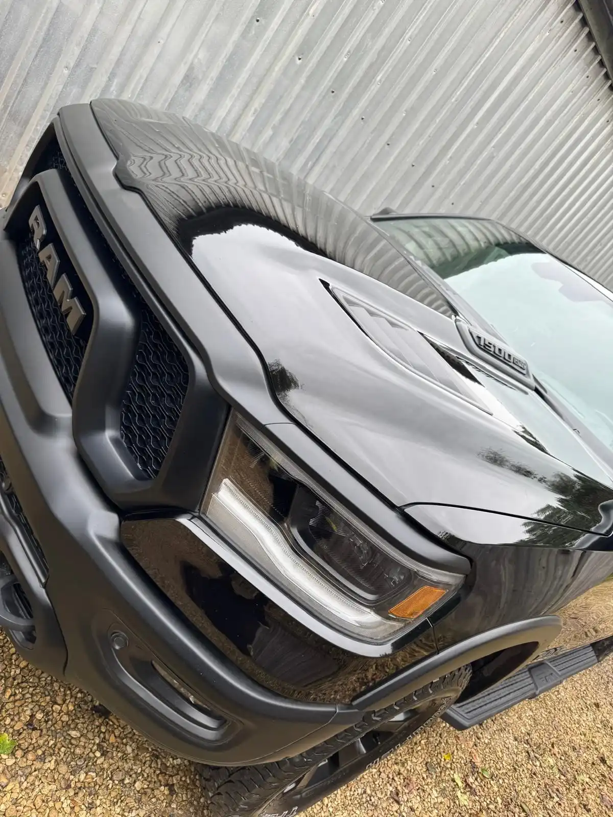 Bonnet and grille of a black RAM 1500, with the reflections running across the black paint