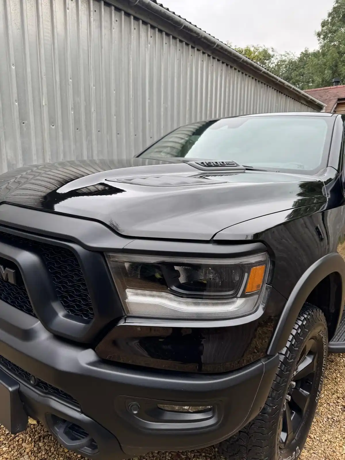 Black RAM 1500 pickup from the front quarter, showing the gloss on the bonnet and the headlamp