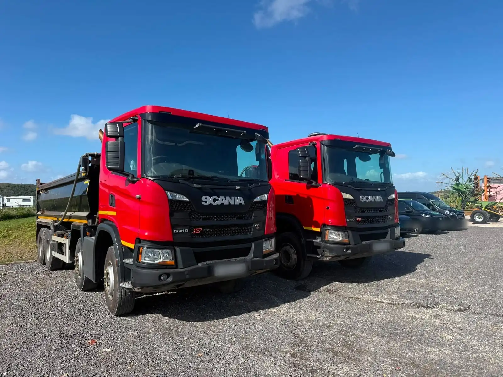 Two red Scania tipper lorries side by side, front quarter view, an example of commercial vehicles