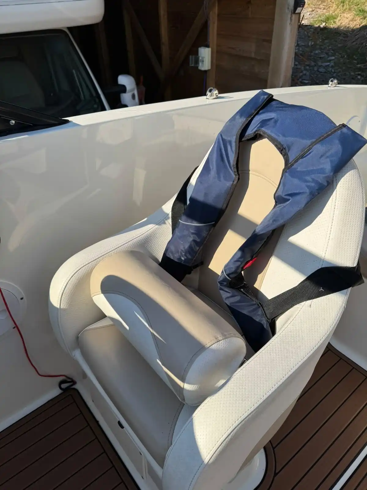Speedboat helm seat in cream upholstery with a life jacket over it, above a wood effect deck