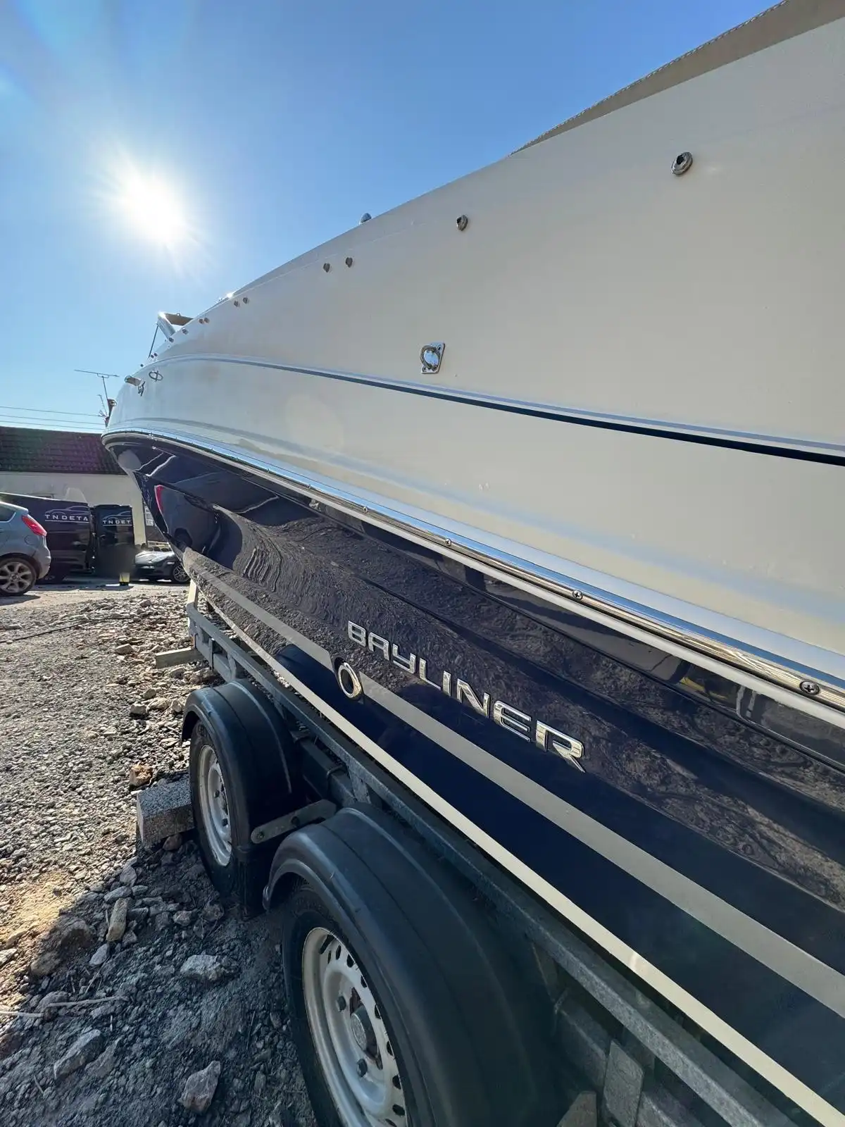 Navy and cream hull of the speedboat on its trailer, showing the Bayliner name and the gloss along the side