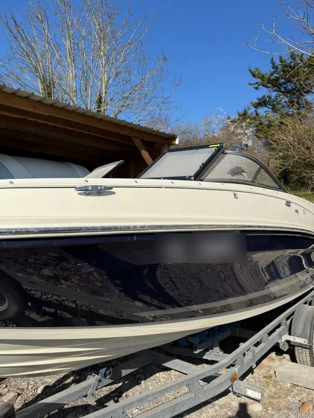 Side of a speedboat hull on its trailer, showing the gloss on the navy and cream hull