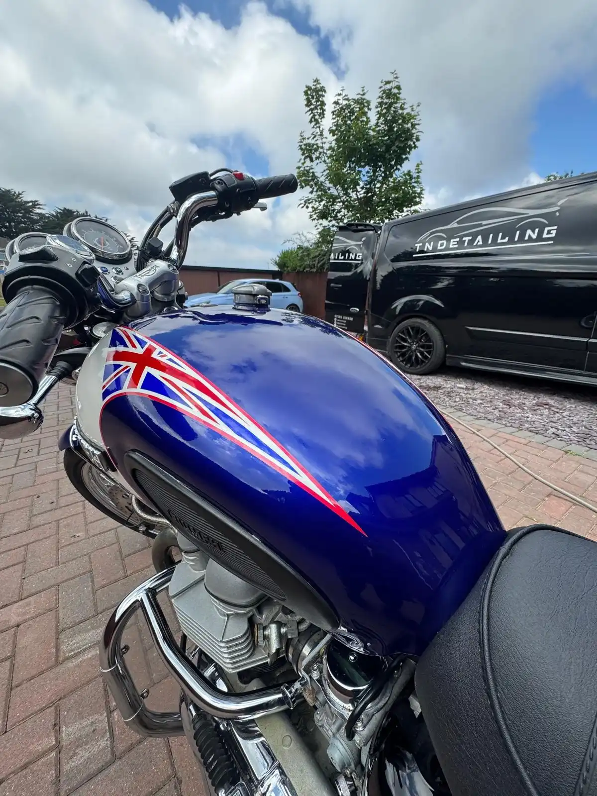 Close view of a Triumph Bonneville tank with a Union Jack design, showing the gloss on the blue paint