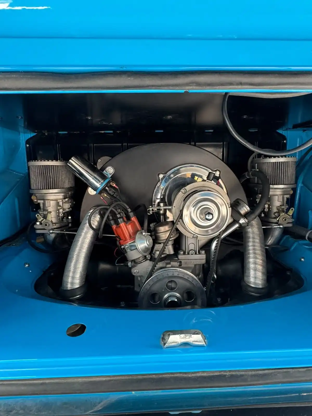 Classic VW air cooled engine in a blue engine bay, with the pipework and fittings clean, an example of an engine bay