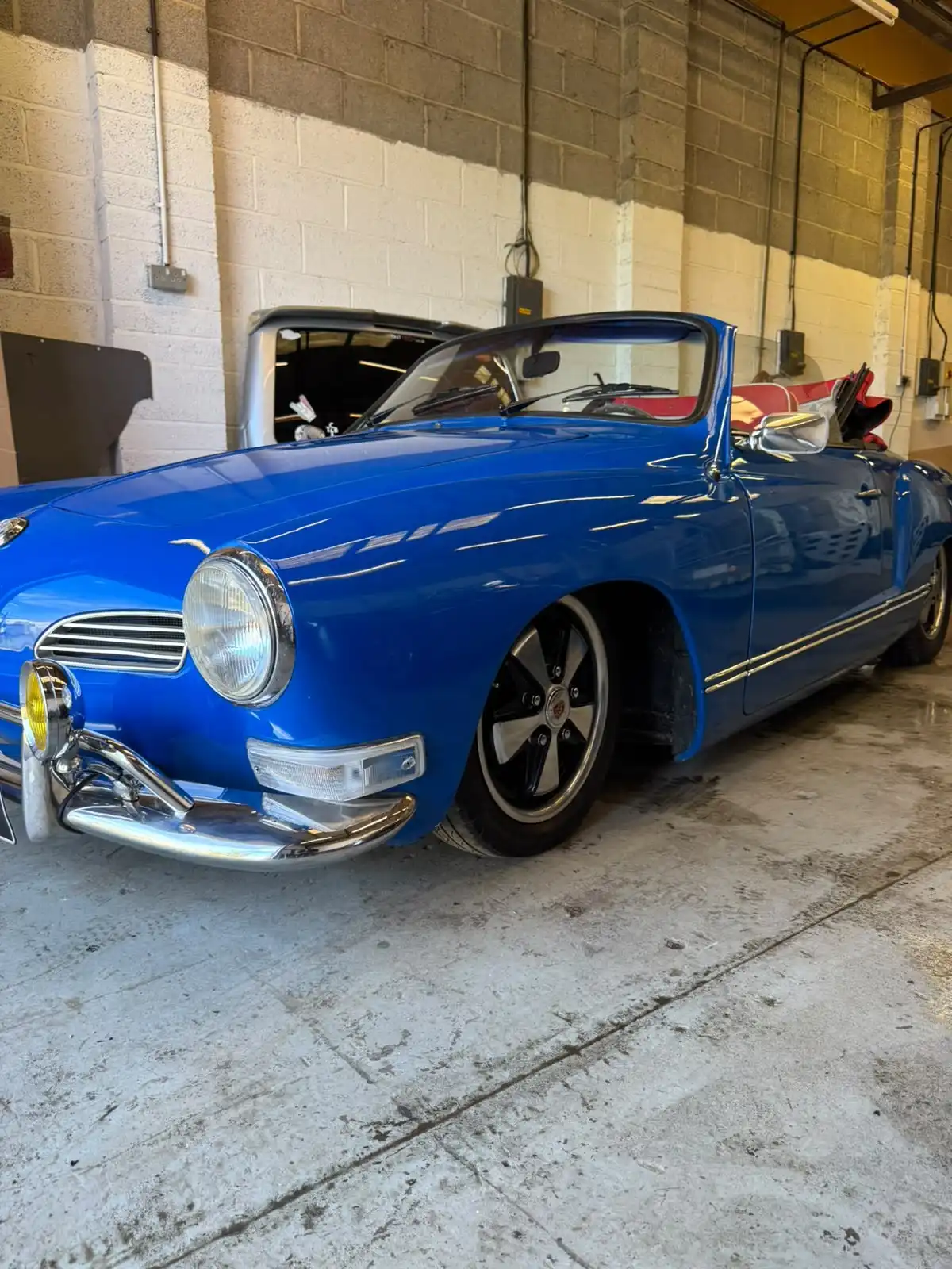 Blue VW Karmann Ghia convertible with the roof folded, front quarter view, an example of a classic car