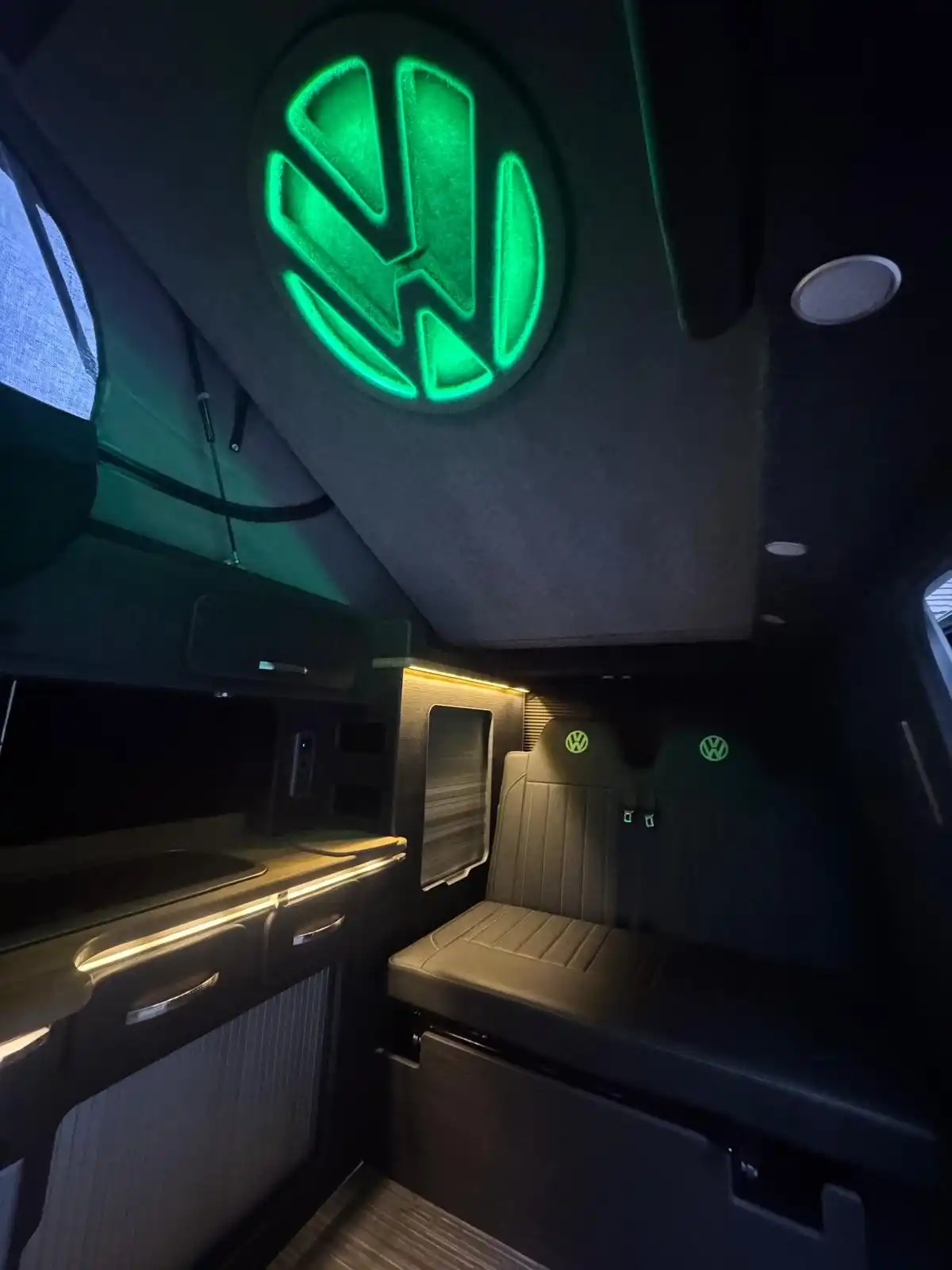 Roof of a VW Transporter camper with a lit green VW logo panel above the kitchen units